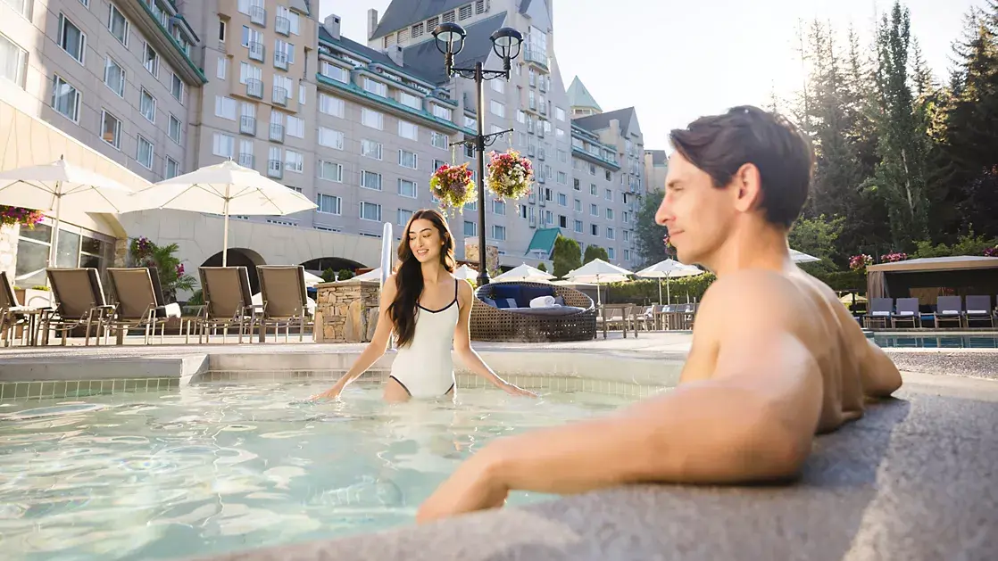 Couple relaxing in the heated outdoor pool at Fairmont Chateau Whistler