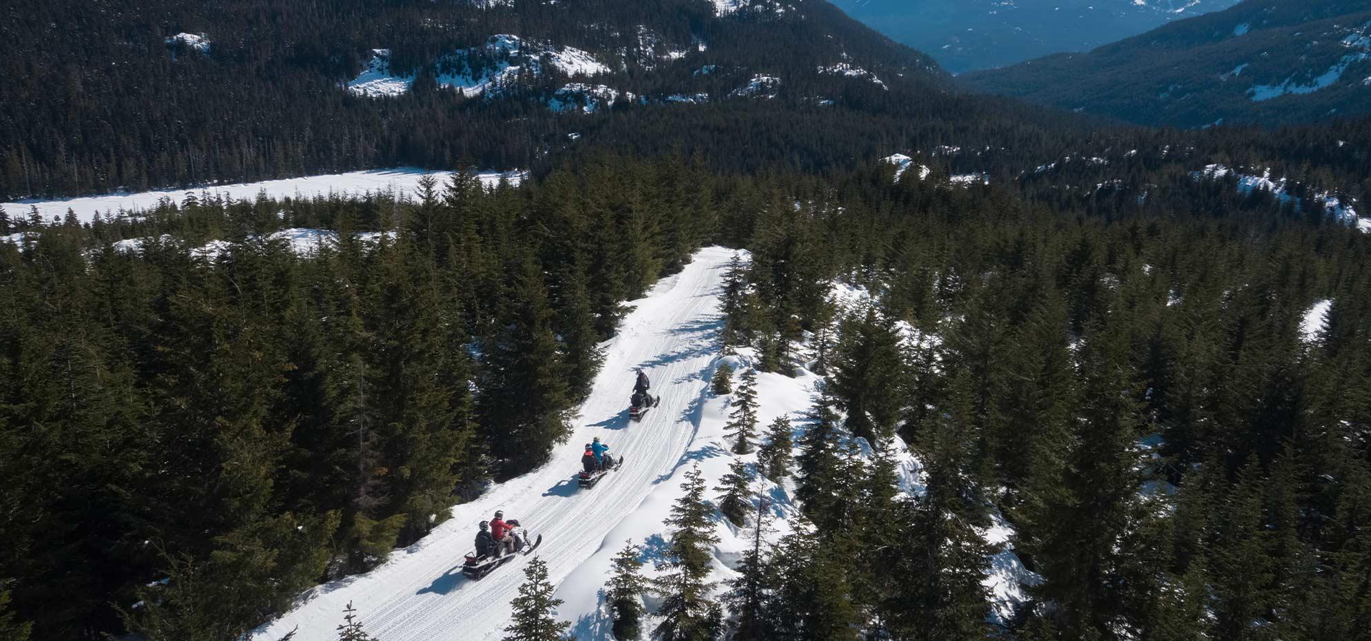 Snowmobilers following a mountain trail through the forest at Cougar Mountain
