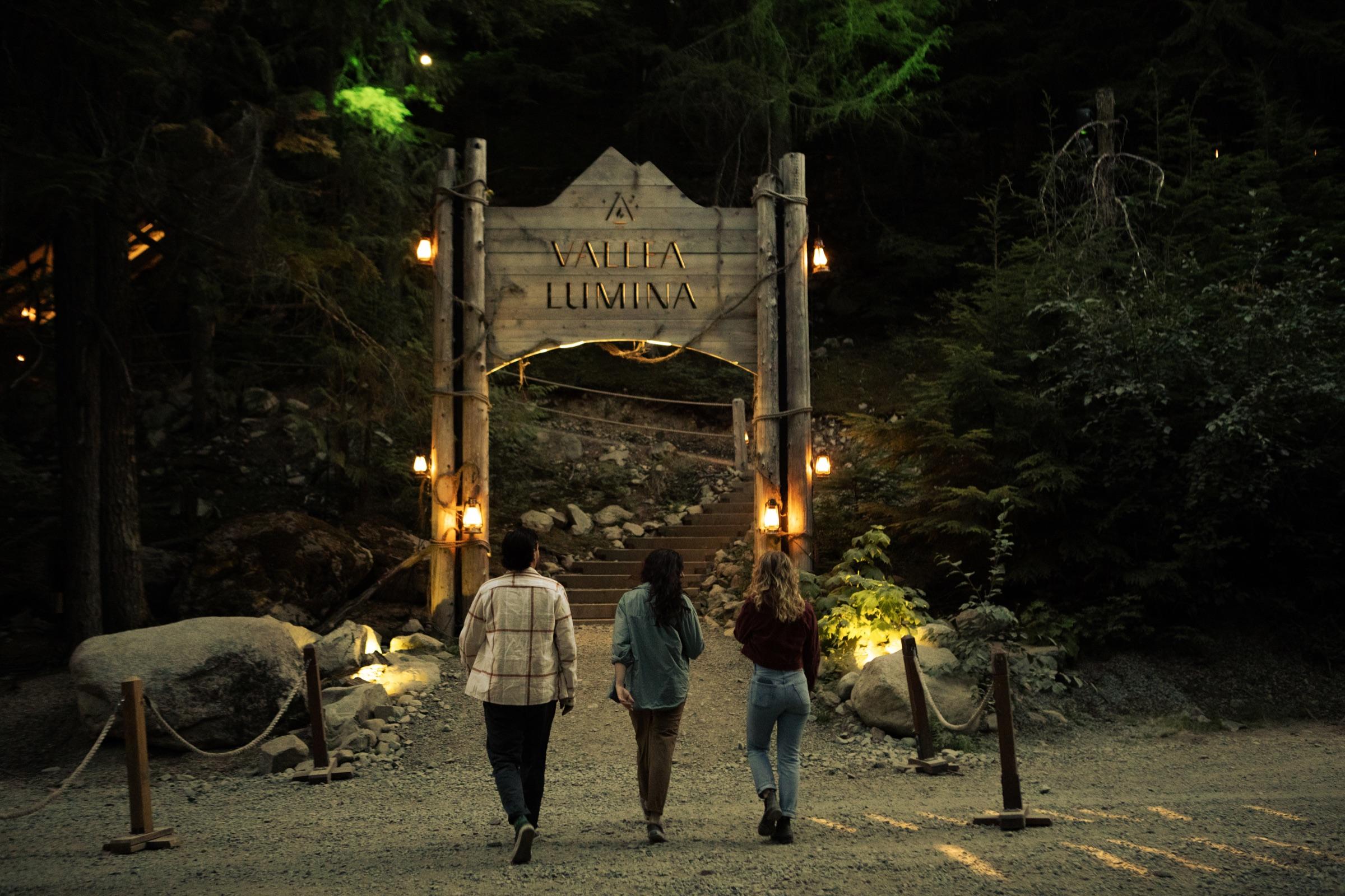 Visitors approaching the illuminated Vallea Lumina entrance in the forest