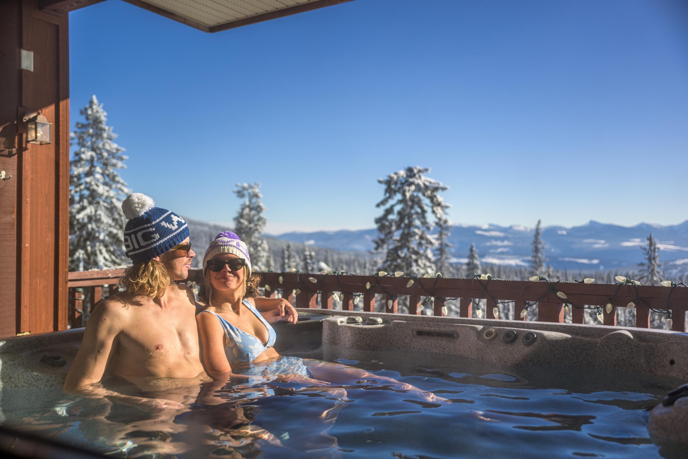 Guests relaxing in a slopeside hot tub at Big White