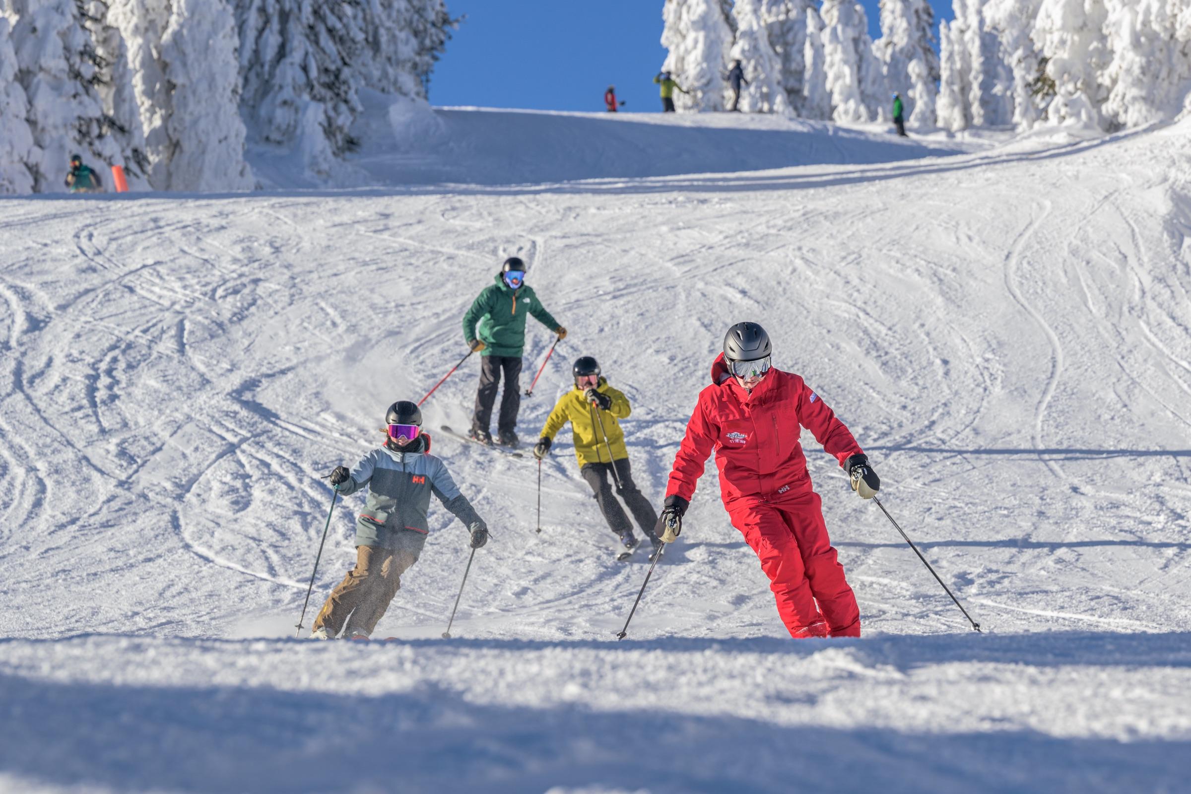 Skiers descending a sunny snow-covered run at Big White