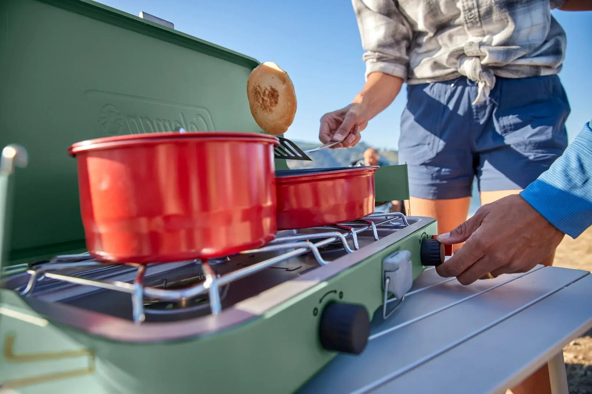 Campers preparing food on a Coleman Cascade two-burner stove